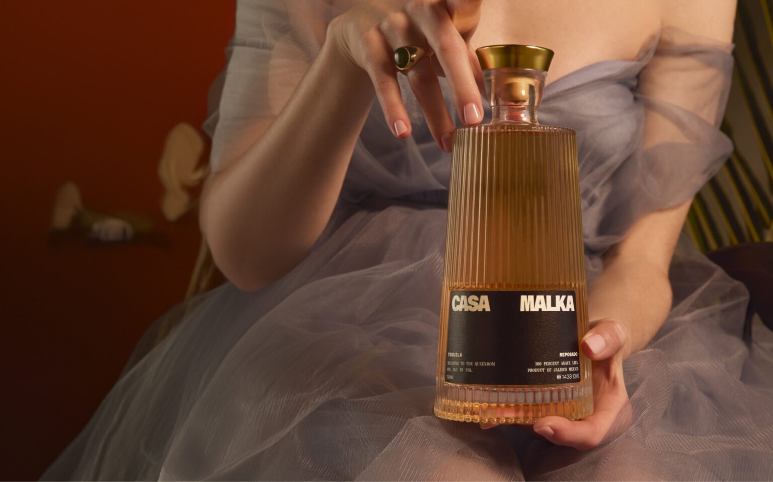 Woman in a dress holding a reposado tequila bottle from Casa Malka