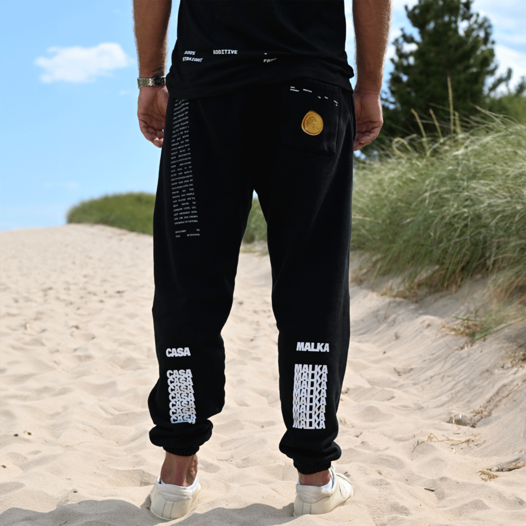 Side view of man wearing black Casa Malka joggers with gold emblem